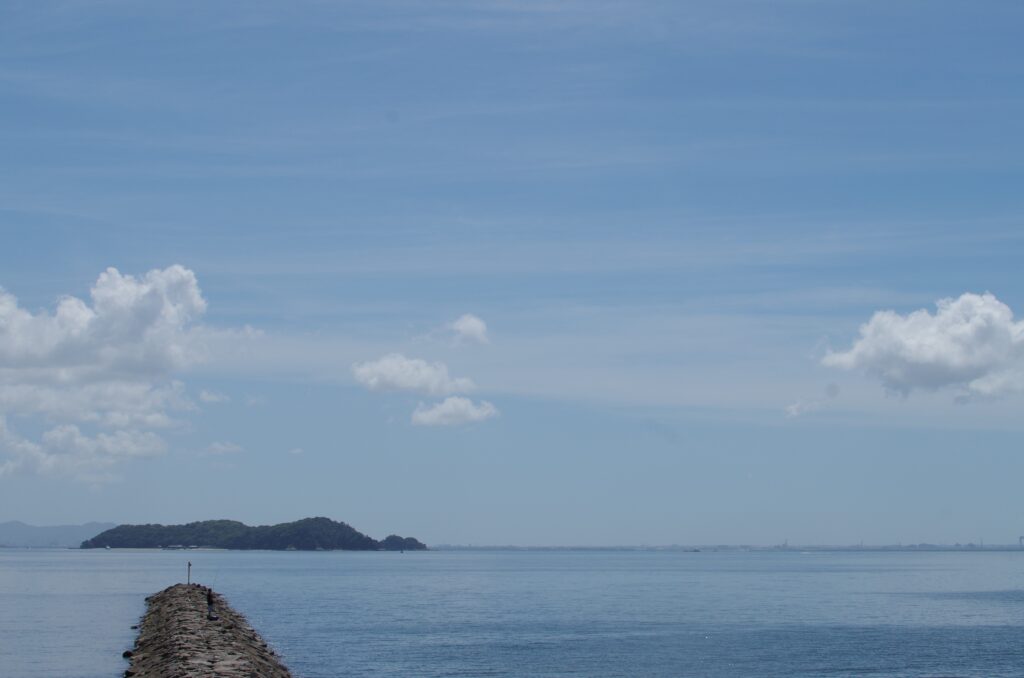 防波堤の先の釣り人と島